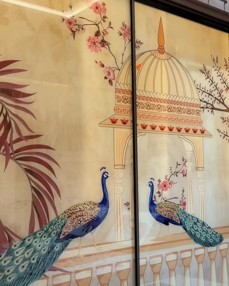 Custom sliding wardrobe doors featuring a traditional Indian art print with blue peacocks, a palatial dome, and delicate floral branches on a warm beige background, framed by a slim black profile.