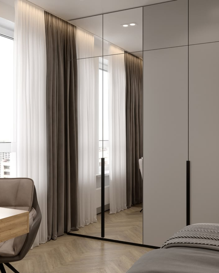 Modern floor-to-ceiling bedroom wardrobe featuring full-length tinted mirror shutters combined with matte grey panels, integrated loft storage, and slim black profile handles.