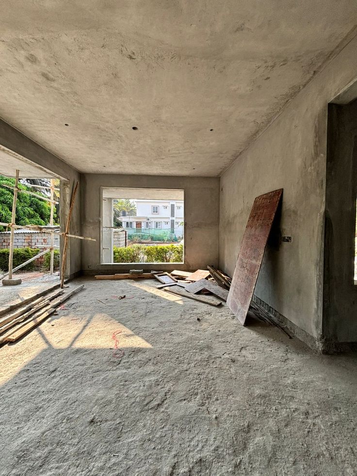 Houseway villa civil construction and plastering stage services in Hyderabad, featuring an under-construction room with raw plastered walls, concrete flooring, scaffolding, and open window frames overlooking greenery.