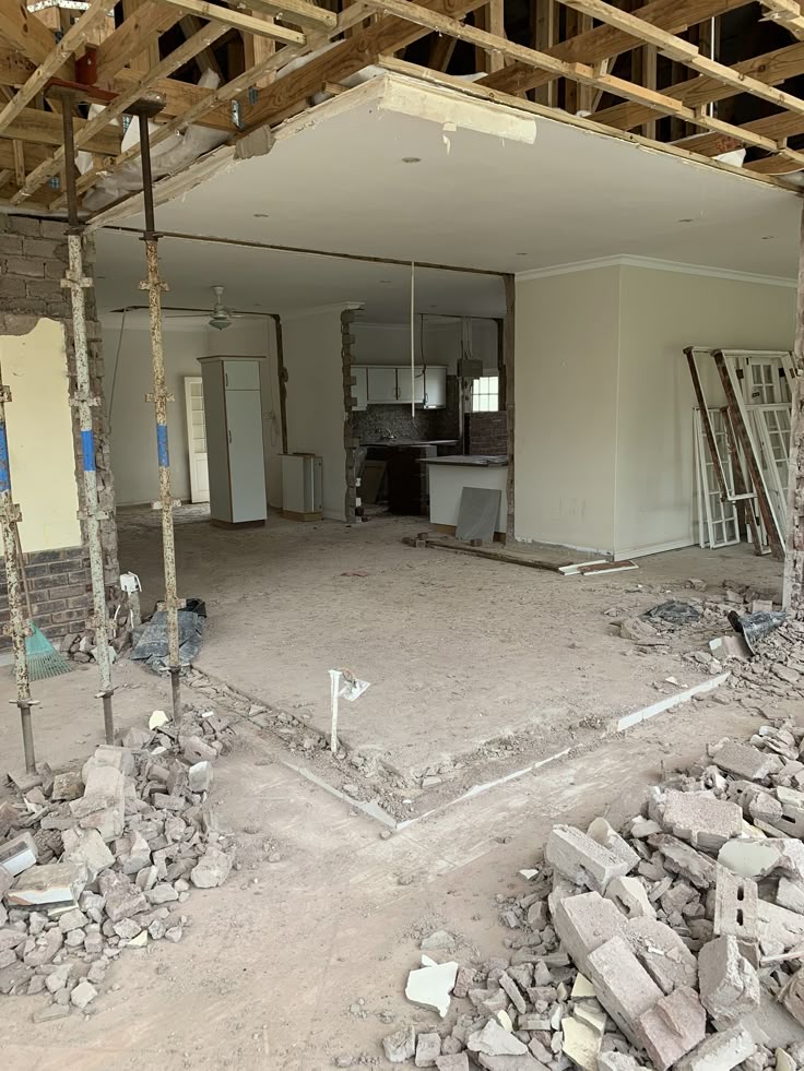 Houseway structural renovation and wall demolition site services in Hyderabad, featuring temporary steel support props, exposed ceiling joists, and rubble from a living room remodeling project